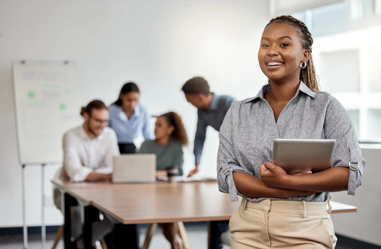 A professional standing with a tablet in a workplace setting